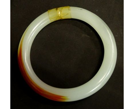 A modern jade bangle, of pale green and orange colour, (AF), 47.2g all in. 