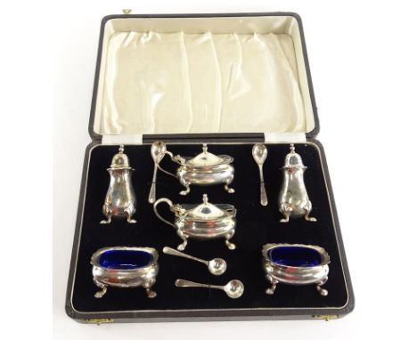 A George VI silver six piece cruet, comprising two mustard pods with covers and shaped legs, each with a blue glass liner, a 