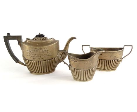 An Edwardian silver three piece tea set, with part fluted decoration, the teapot with ebonised knop and handle, presentation 