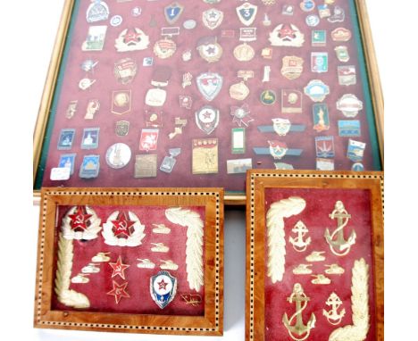FRAMED COLLECTION OF MAINLY GILT METAL AND ENAMEL BADGES RELATING TO COMMUNIST RUSSIA, many featuring the hammer and sickle w