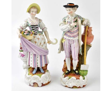 A pair of ceramic figures, the lady with a basket of flowers, the man leaning on watering can holding flowers, height of larg