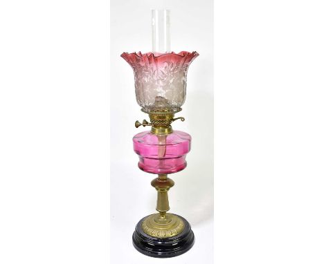 A Victorian oil lamp, the cranberry and clear glass shade with pinched rim, decorated with floral sprays above the cranberry 