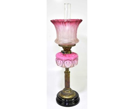 A Victorian oil lamp with cranberry and clear glass shade with etched floral decoration above the cranberry and milk glass re