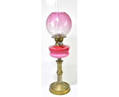 An early 20th century oil lamp, the cranberry and milk glass shade with etched floral decoration above cranberry and milk gla