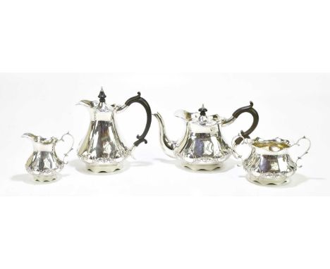 REID &amp; SONS; an Edward VII hallmarked silver four piece tea service with repoussé scrolling decoration to the lower body,