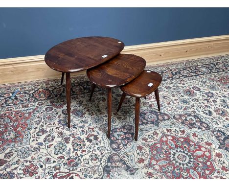 ERCOL; a nest of dark elm pebble coffee tables, on turned column supports.