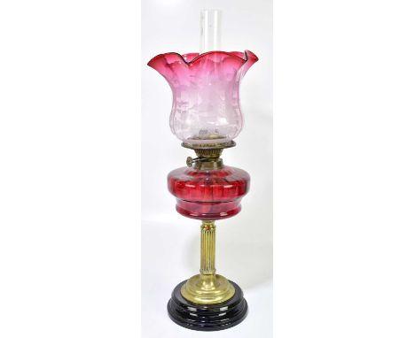 A Victorian oil lamp, the cranberry and clear glass shade with wavy rim, unusually decorated with tigers in landscape setting