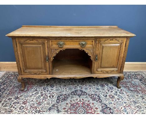 A 19th century light oak sideboard, with a shaped drawer above dog kennel, flanked by a pair of panelled doors on cabriole su