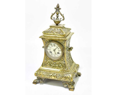 A late 19th/early 20th century French brass mantel clock with cast decoration of scrolling motifs and urn finial above the ci