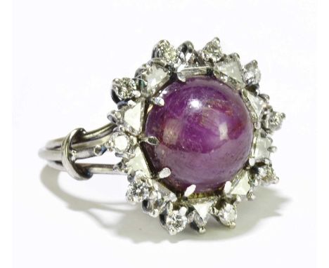 A white metal star ruby and diamond set large cluster ring, the claw set central ruby within a border of trapezium and round 