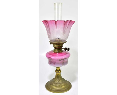 A late 19th century oil lamp, the cranberry and clear glass shade, with wavy rim, with etched floral decoration above the cra
