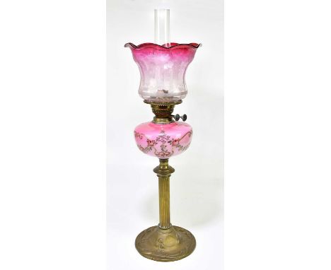A late 19th century oil lamp with cranberry and clear glass shade with frosted decoration of floral sprays above the cranberr