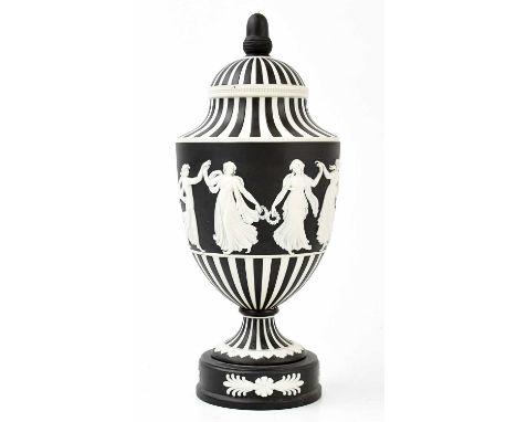 WEDGWOOD; a black basalt pedestal urn and cover, with black and white fluted decoration above a single band of classical maid