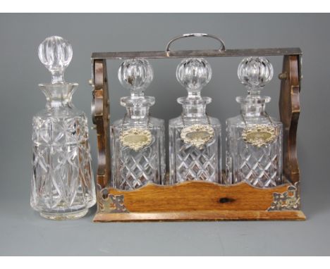 A wood and silver plated tantalus with three cut glass decanters and hallmarked silver spirit labels together with another cu