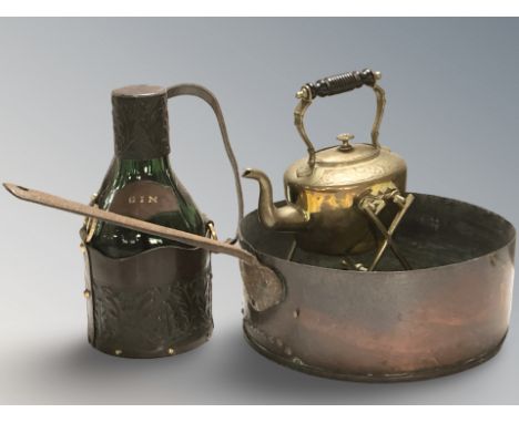 A large copper steel handled pan, length 60 cm, a brass spirit kettle on stand and a green glass gin bottle in leather carrie