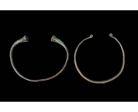 Ca. 200 BC – AD 100.A pair of Celtic bronze necklaces/torques. The first is composed of a round hoop with a circular section 