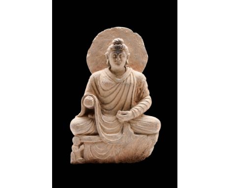 Ca. AD 100 - 200.A beautifully carved schist Buddha seated in the Dyana mudra position and backed with a halo. He sits on a c