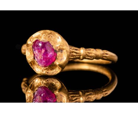 Ca. AD 1300 - 1500.A Medieval 23.5 ct gold ring with bezel securing a circular ruby cabochon. The band is decorated with a mo