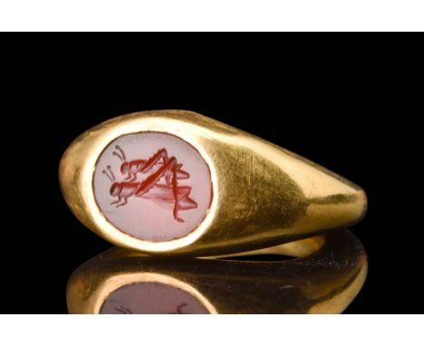 Ca. AD 100 - 200.A gold finger ring set with a carnelian intaglio featuring a delightful portrayal of two grasshoppers, one p