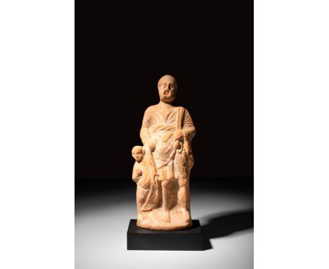 Ca. late 4th to 2nd century BC.A mould-made ceramic votive figure of rare form, featuring a man holding the arm of a small ch
