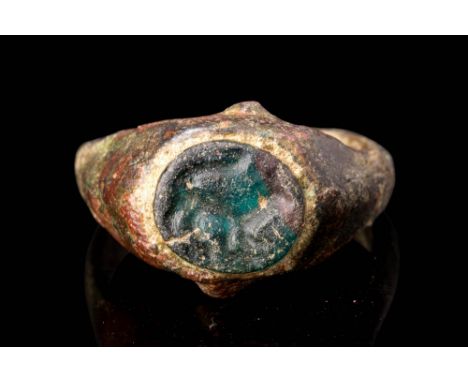 Ca. AD 100 - 200.A Roman bronze finger ring decorated with a glass intaglio depicting a skunk facing right; round-sectioned h