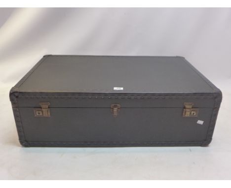 A vintage black trunk with nailed leather border and brass hardware locks, interior with grey and white paper lining, L.87cm,