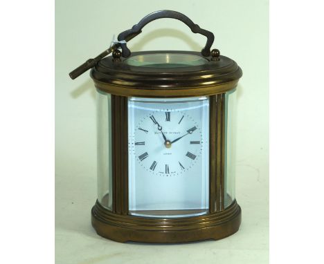 A Matthew Norman brass cased oval carriage clockThe white enamel face with Roman numberals, impressed Swiss made to base, hei