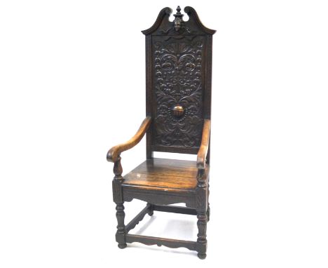 A 17th Century style carved oak high back open sided armchair, 20th CenturyFeaturing a broken arch and mask pediment above th