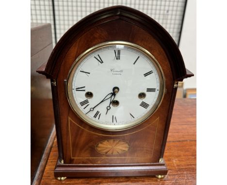 A mahogany mantle clock, of pointed form, inlaid with an oval fan, with an enamel dial and Roman numerals