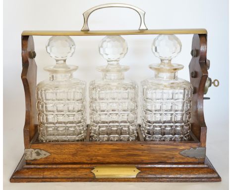 A brass mounted oak three decanter tantalus, 37cm wide. Condition - fair to good