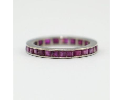 A white metal and rectangular cut ruby set full eternity ring, size M/N, gross weight 3.5 grams. Condition - fair
