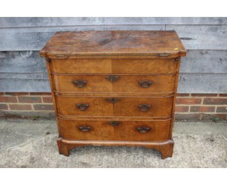 A bachelor's figured walnut break bowfront fold over top chest with baize lined interior and writing compartment over three l