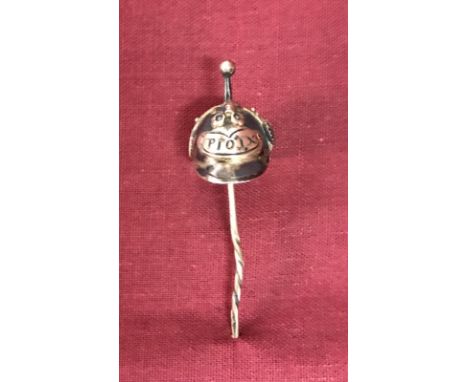 A white metal stick pin of a WW1 German Pickelhaube helmet. In wooden display mount. 