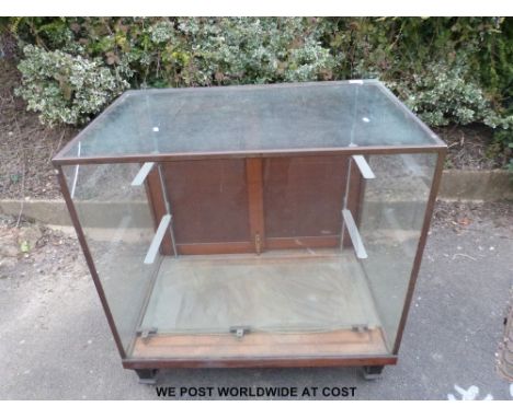 A glazed haberdashery or shopfitting cabinet with brass frame, sliding rear doors and metal shelf brackets within (W91.5 x H9