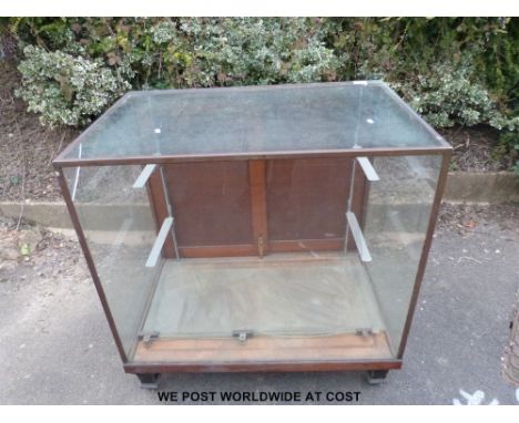 A glazed haberdashery or shopfitting cabinet with brass frame, sliding rear doors and metal shelf brackets within (W91.5 x H9