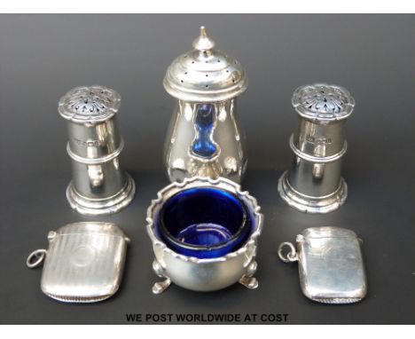 A pair of hallmarked silver peppers, a further silver pepper, open salt with blue glass liner and two hallmarked silver vesta