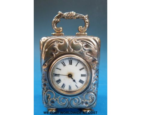 An Edward VII embossed hallmarked silver miniature carriage or dressing table clock, raised on ball feet, with swing handle, 