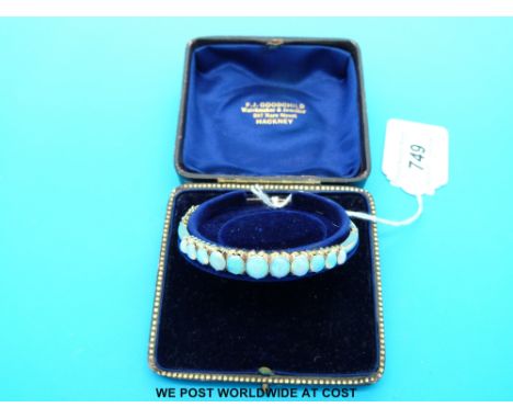 A yellow metal bangle marked 9ct set with 11 graduated oval opal cabochons, in original box