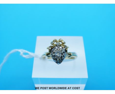 A yellow metal ring set with an old cut diamonds surrounding a pear cut diamond of approximately 0.15ct (Size K)