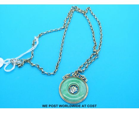 A yellow metal pendant set with a jade bi disc on a 9ct gold chain