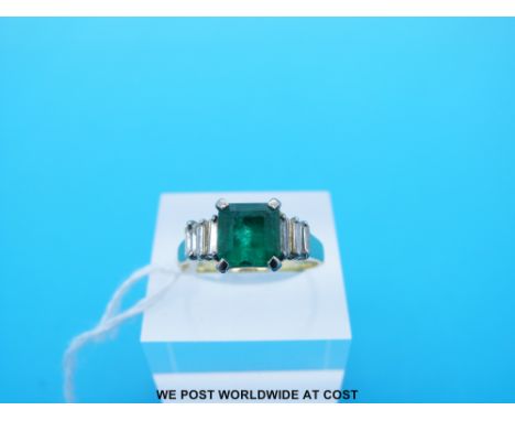 A yellow metal ring set with an Asscher cut emerald of approximately 1.77ct and three baguette cut diamonds to each shoulder 