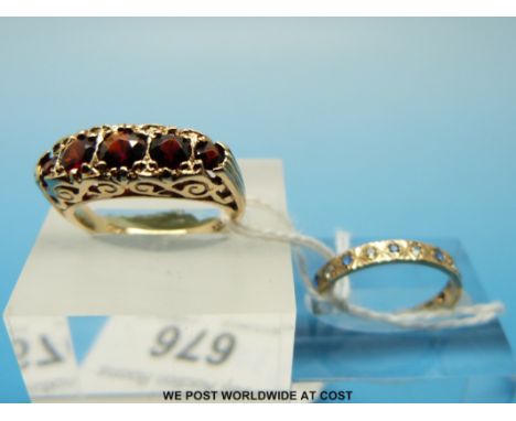 A 9ct gold ring set with five round cut garnets in a scrolling setting and a 9ct gold ring set with clear and blue stones, si