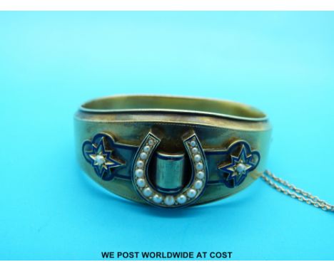 A Victorian bangle set with seed pearls in a horseshoe design and with blue enamel star decoration