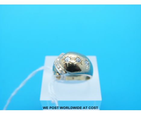 A yellow metal ring set with three diamonds in star setting and a further row of diamonds (Size K)