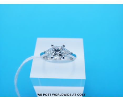 An 18ct white gold ring set with a princess cut diamond measuring 1ct flanked by triangular cut diamonds to each side (Size K