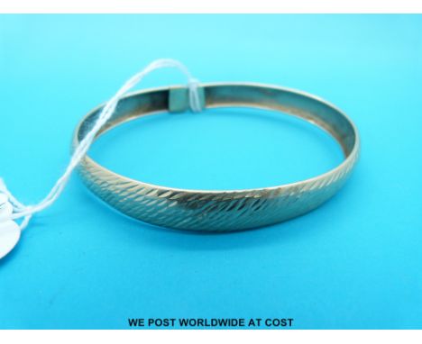 A yellow metal bangle marked 10k with textured surface (6g)