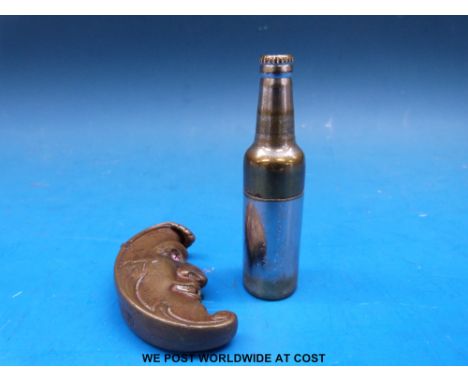 A brass vesta formed as a man in the moon with jewelled eyes and a lighter in the form of a bottle.