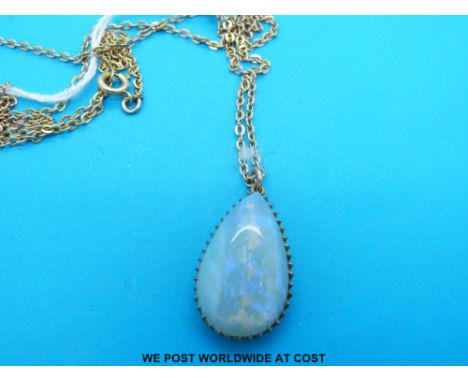 A gold pendant set with a pear shaped opal cabochon on a yellow metal chain