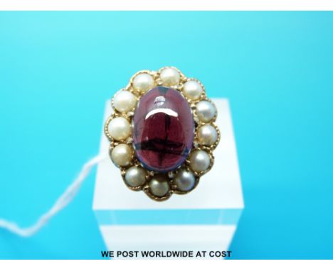 A 9ct gold  ring set with a garnet cabochon surrounded by pearls, size Q/R (7.6g)