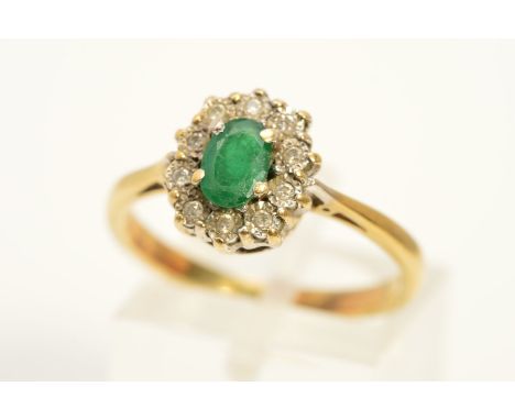 AN EMERALD AND DIAMOND CLUSTER RING, the central oval emerald within an illusion set, brilliant cut diamond surround, total d